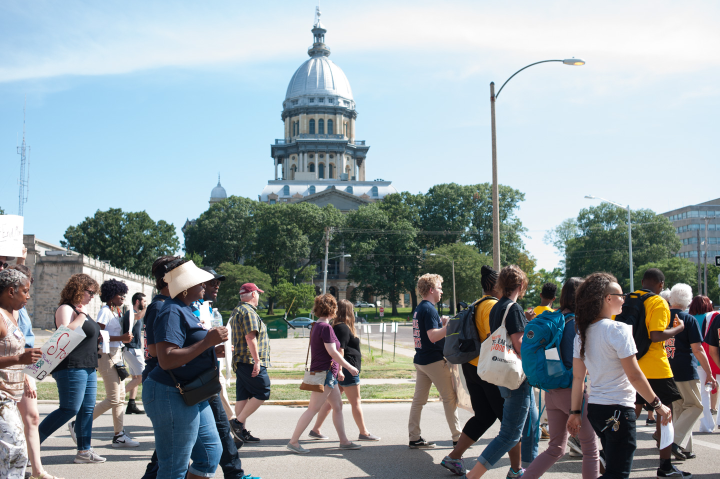 A group of protestors walk by the Illinois State Capitol building holding signs