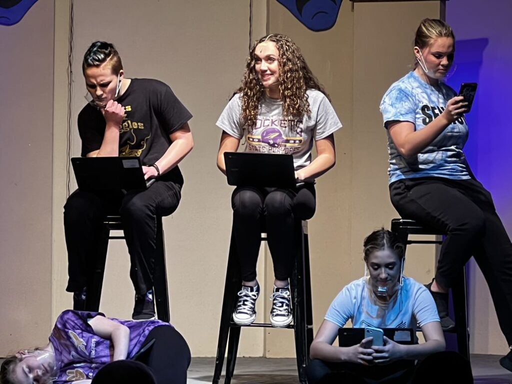 5 students participating in the "Losing Normal" project 3 sitting on stools and to sitting on the stage