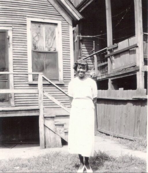 A Young Gwendolyn Brooks standing in the back yard in a white dress