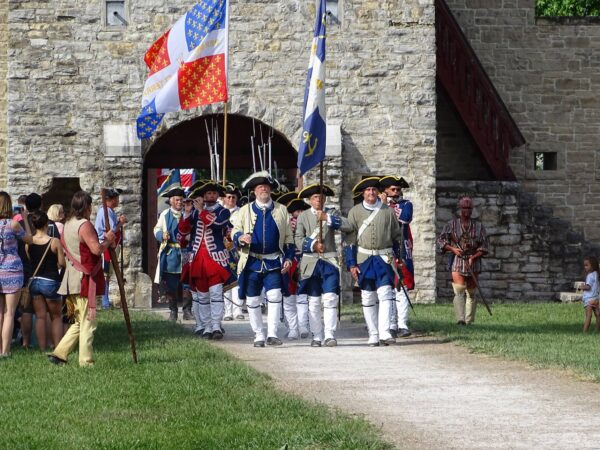 017 Annual Fort de Chartres Rendezvous -- people in period costume marching from the Forte entrance with flags