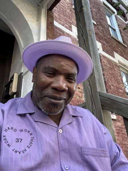 Justice-Impacted Community Worker Renaldo Hudson in a purple hat and purple shirt